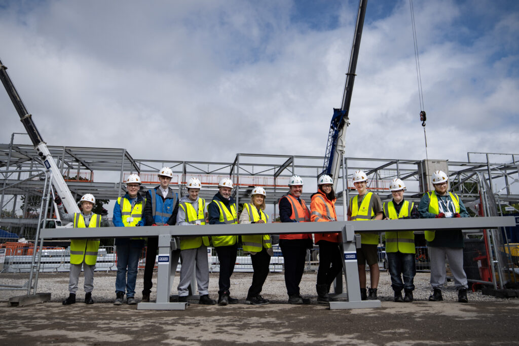 Students, staff and contractors in high viz jackets standing along
