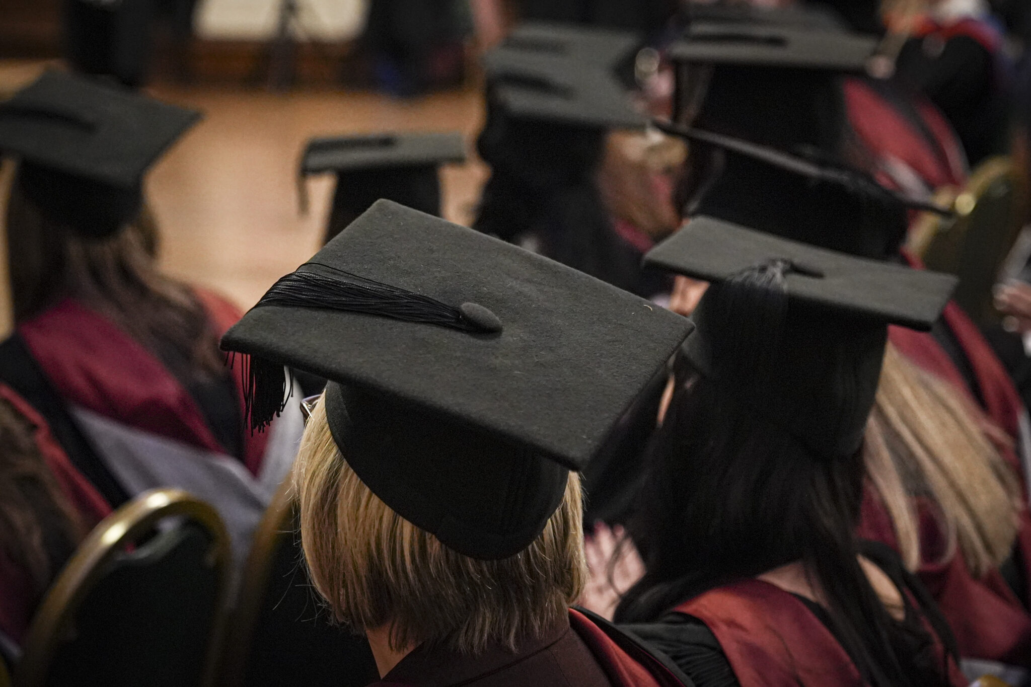 image from the back of multiple people wearing graduation mortar boards