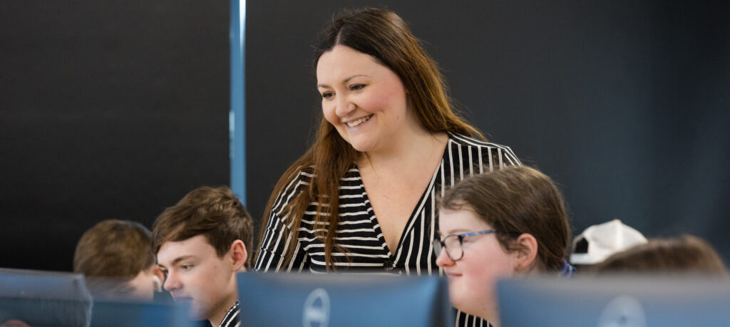 tutor smiling with students in computer lab