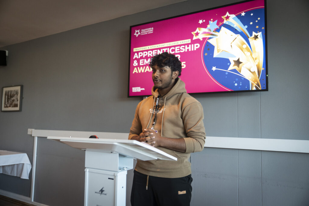 A person stands at a podium addressing an audience.