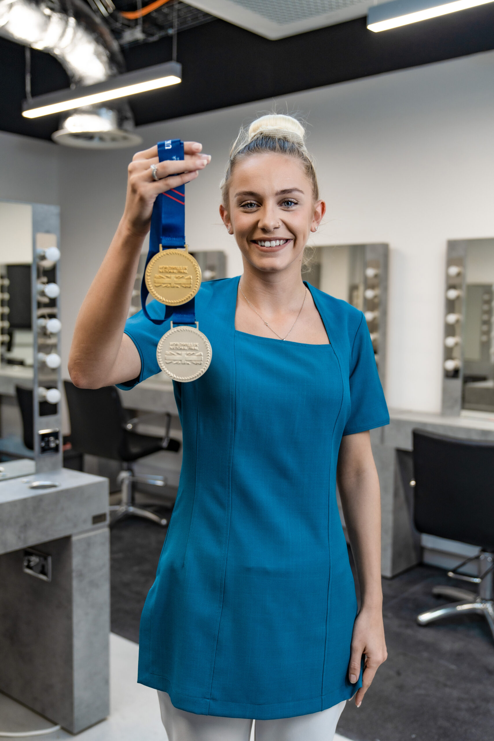Girl holding up two medals, gold and silver while smiling