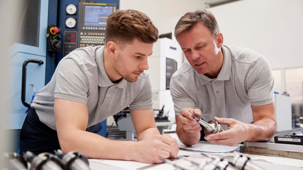 male apprentice and male tutor working on machinery