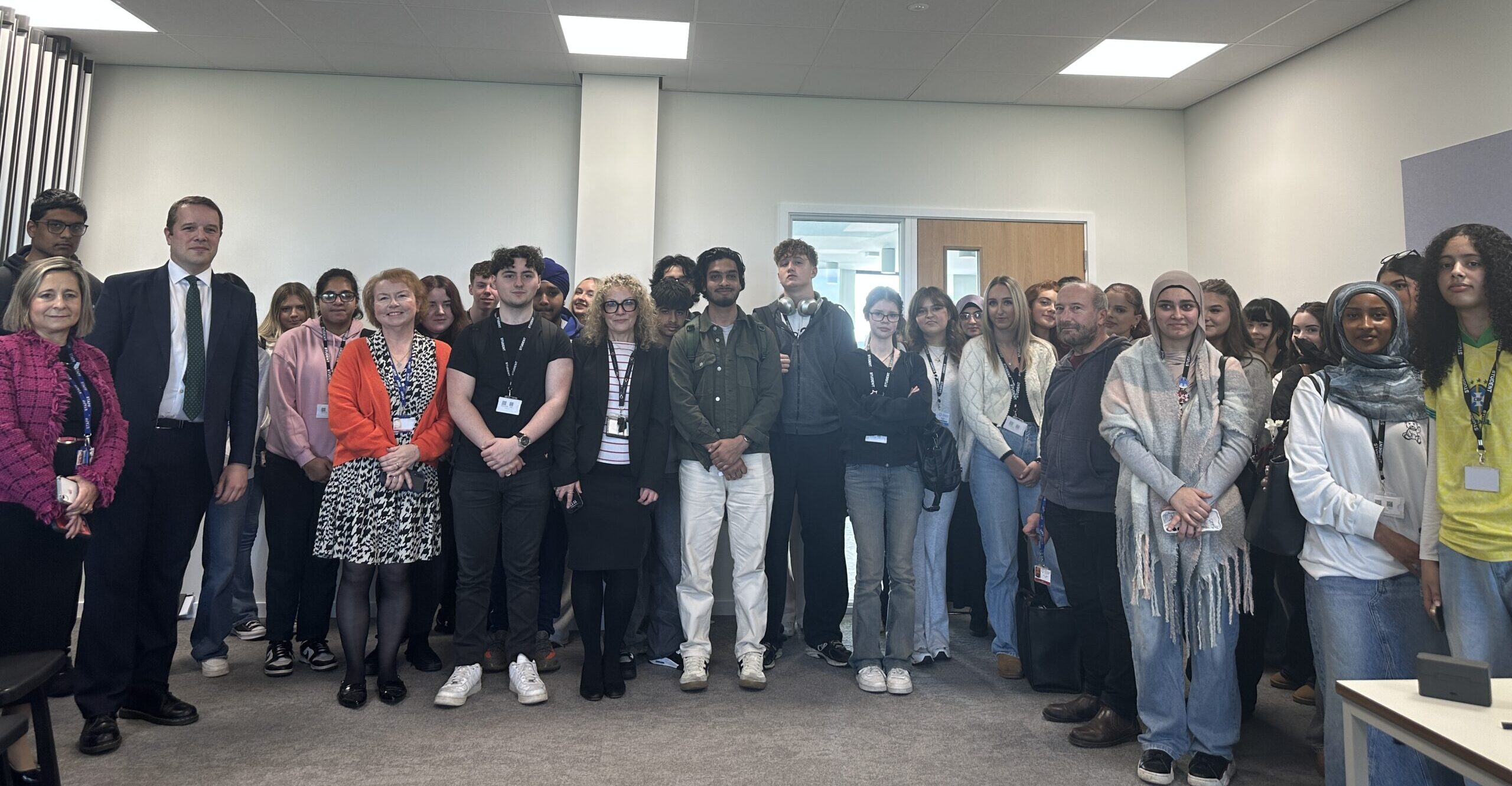 Group photo of college students and staff gathered in a classroom setting with MP Tom Morrison.