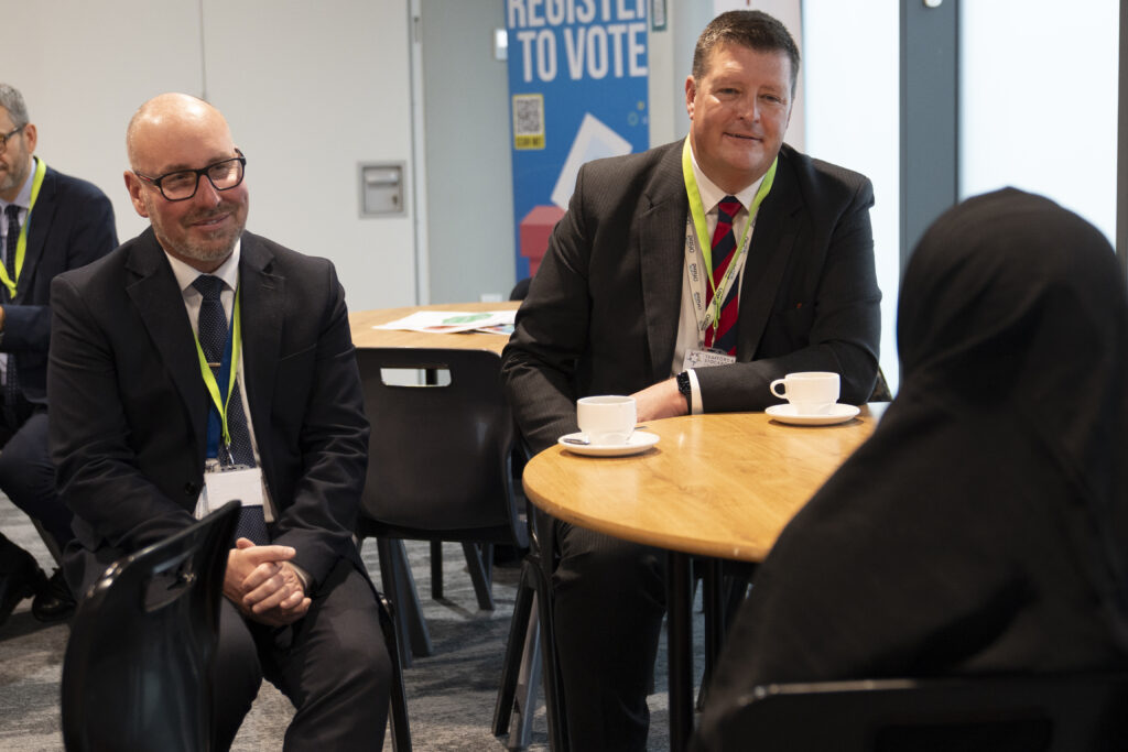 College meeting in a modern conference room with participants seated around a round table, discussing academic programs and student opportunities.